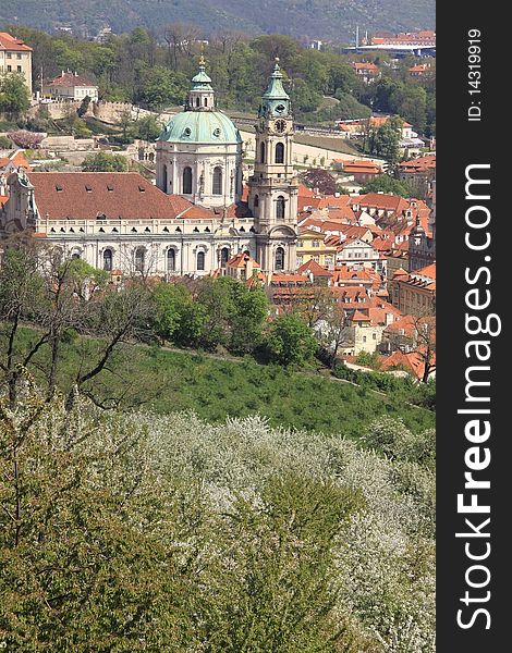 View on Prague's St. Nicholas' Cathedral with flowering trees and green grass