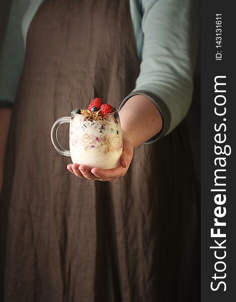 Woman Holding A Glass Jar With Granola, Yogurt And Berries. Vertical.