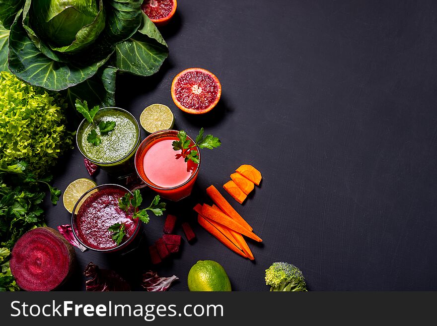 Different healthy vegan drinks with fruits and vegetables on the black wooden background. Flat lay.