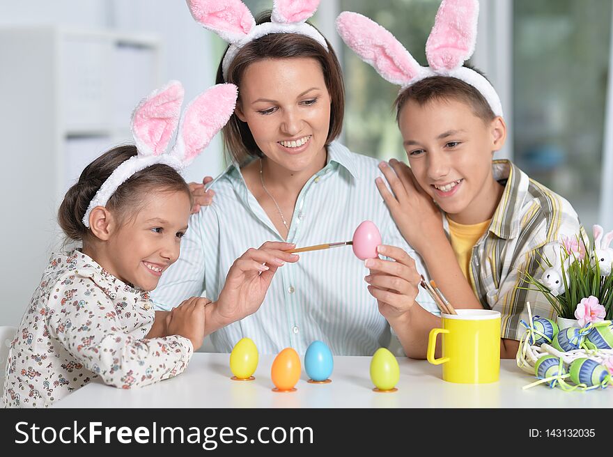 Portrait of family painting traditional Easter eggs in different colors at home with pleasure preparing to religious spring holiday