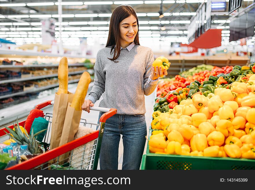 Woman choosing fresh sweet yellow peppers