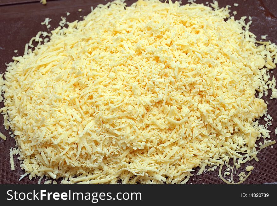 Pile of grated cheese on the threaded board