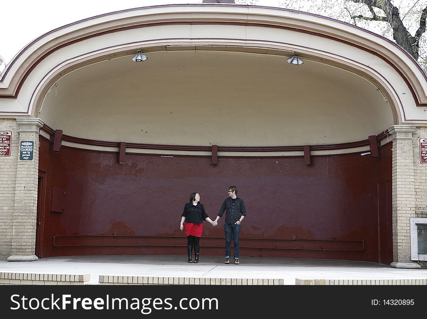 Young college age couple holding hands in love standing on outdoor stage. Young college age couple holding hands in love standing on outdoor stage