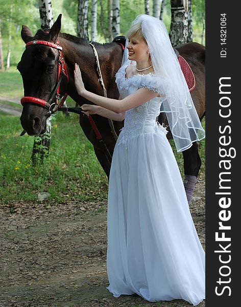 Portrait of the bride in a white dress with a diadem in hair  and red rose in  spring garden