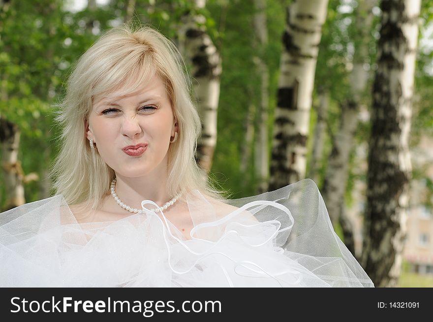 Portrait of the bride in a white dress with a diadem in hair  and red rose in  spring garden