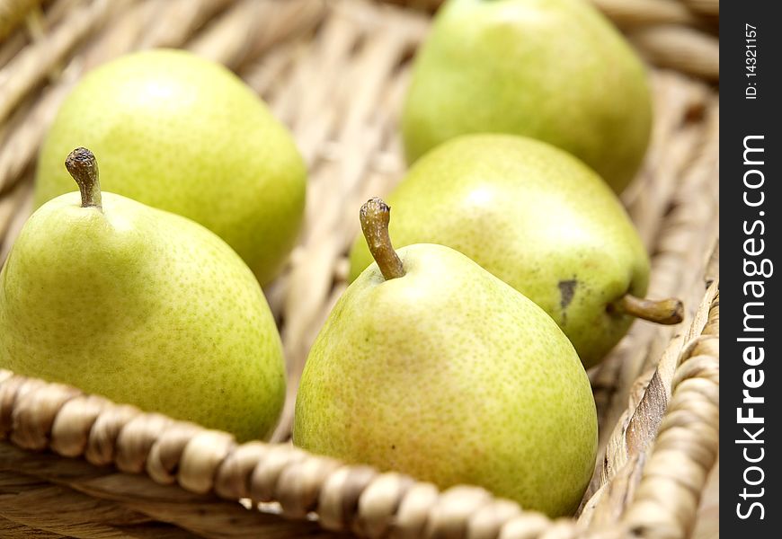 Five green pears in a basket