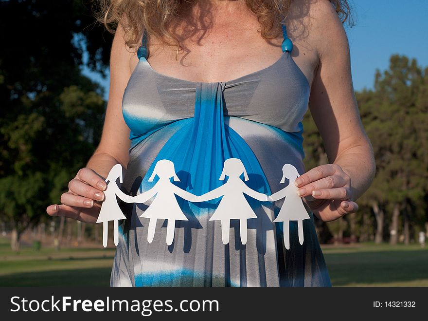 Pregnant woman holding small paper girls. Pregnant woman holding small paper girls