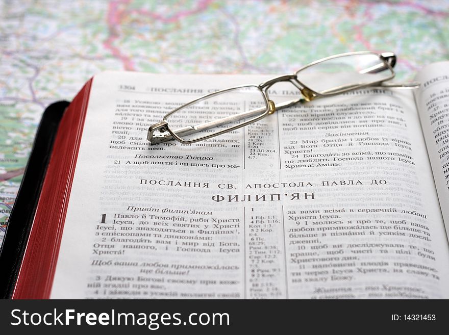 Bible in the Ukrainian language and glasses on map background. Bible in the Ukrainian language and glasses on map background