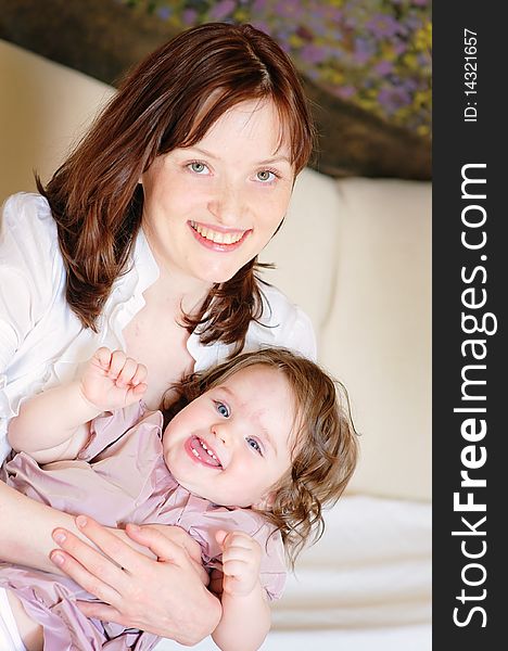 Beautiful mother hugs her 9-months baby-daughter and smiling closeup. Beautiful mother hugs her 9-months baby-daughter and smiling closeup