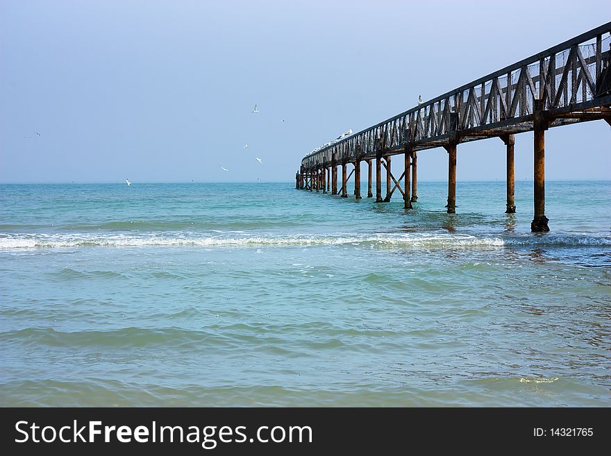 Old iron footbridge - pier with seagull over calm sea - a tranquil marine scene. Old iron footbridge - pier with seagull over calm sea - a tranquil marine scene