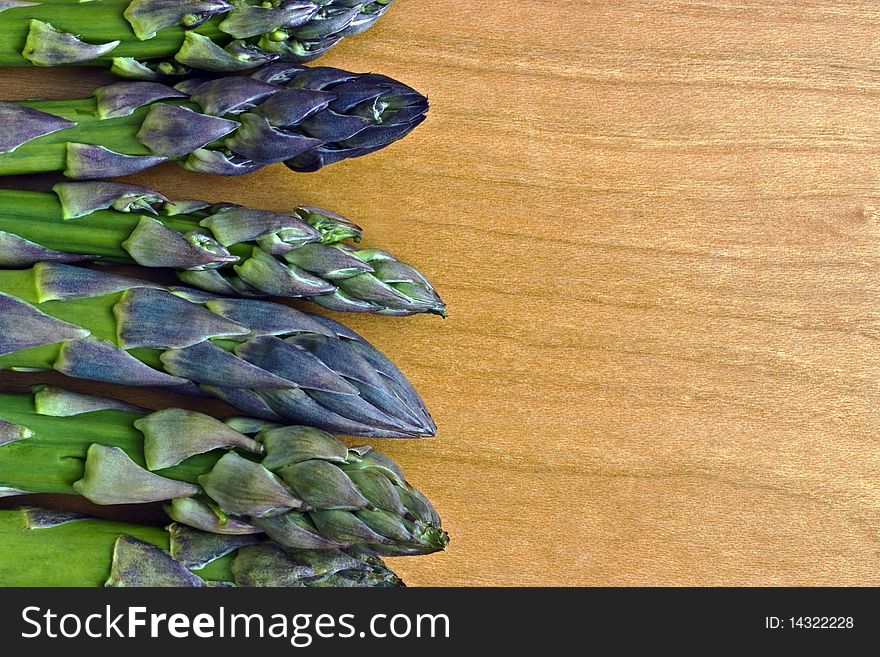 Uncooked asparagus tips on a wooden board