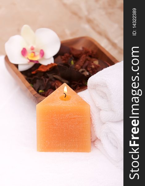 Spa candle with white rolled up towels