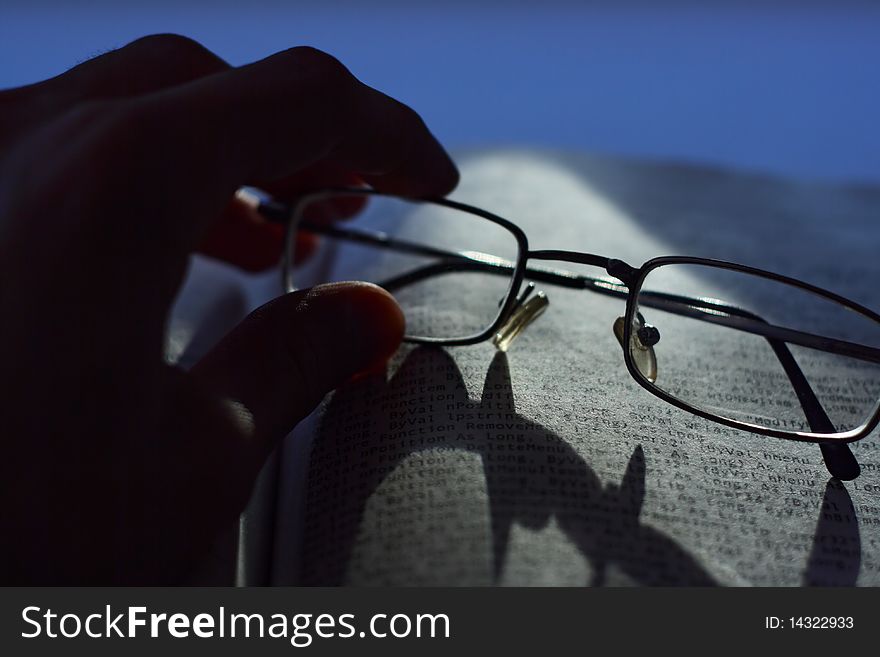 Reading of the book. The hand holds glasses