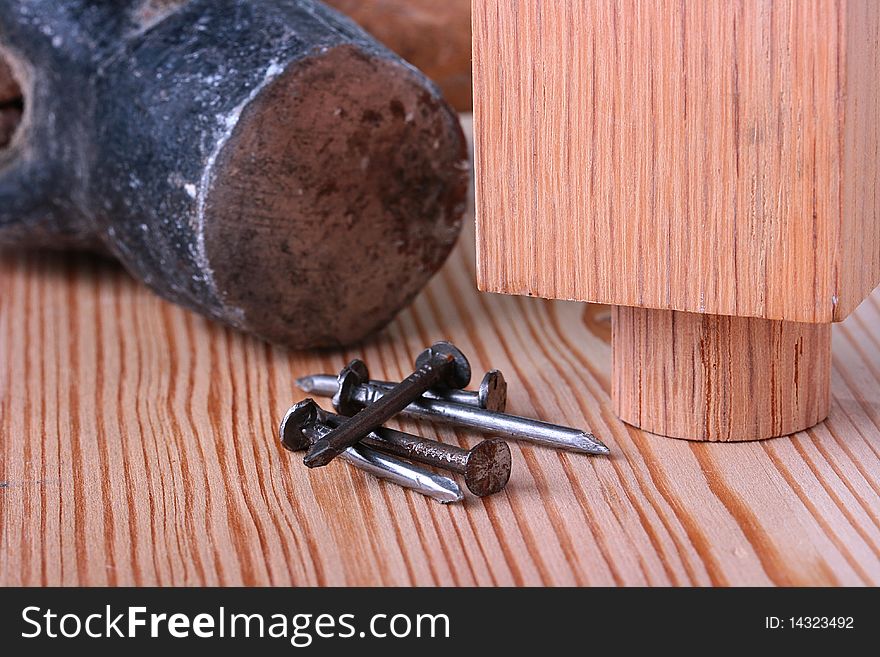 Nails on a wooden table with a hammer and a wooden product.