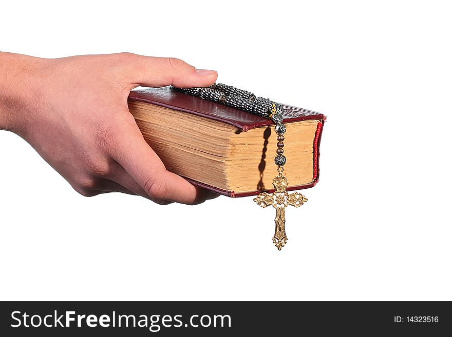The man's hand holds the old bible with a cross on a chain.
