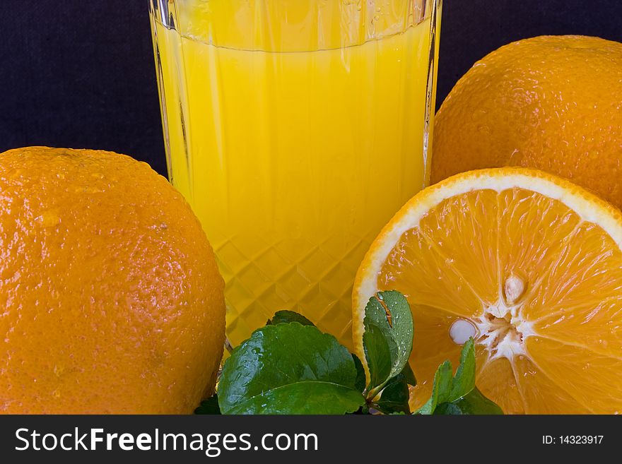 A group of oranges with leaf and a glass of juice. A group of oranges with leaf and a glass of juice