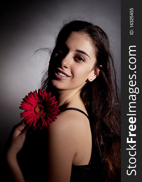 Attractive woman with red flower on black background