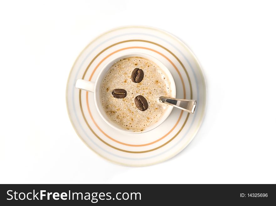 Top view of a coffee cup filled with capuccino and coffee beans