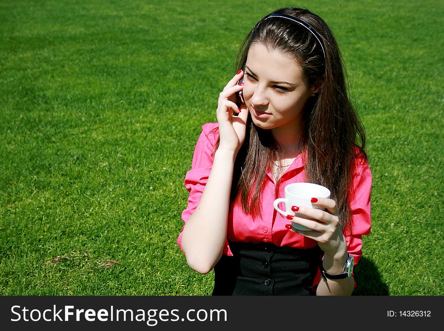 Young businesswoman drinking tea and talking by phone