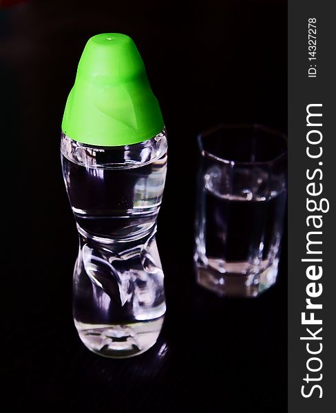 A bottle of fresh water with a cup isolated on blackground. A bottle of fresh water with a cup isolated on blackground