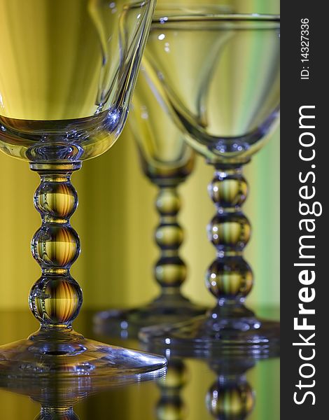 Three wine glasses on yellow background with detailed focus on front glass. Three wine glasses on yellow background with detailed focus on front glass