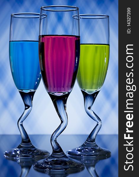 Blue, pink, and green, liqueur glasses on blue and white background. Blue, pink, and green, liqueur glasses on blue and white background