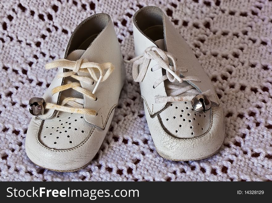 Soft white leather baby shoes on a white crochet baby blanket