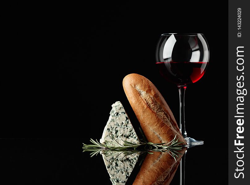 Blue cheese with bread, rosemary and red wine on a black reflective background. Copy space for your text. Blue cheese with bread, rosemary and red wine on a black reflective background. Copy space for your text