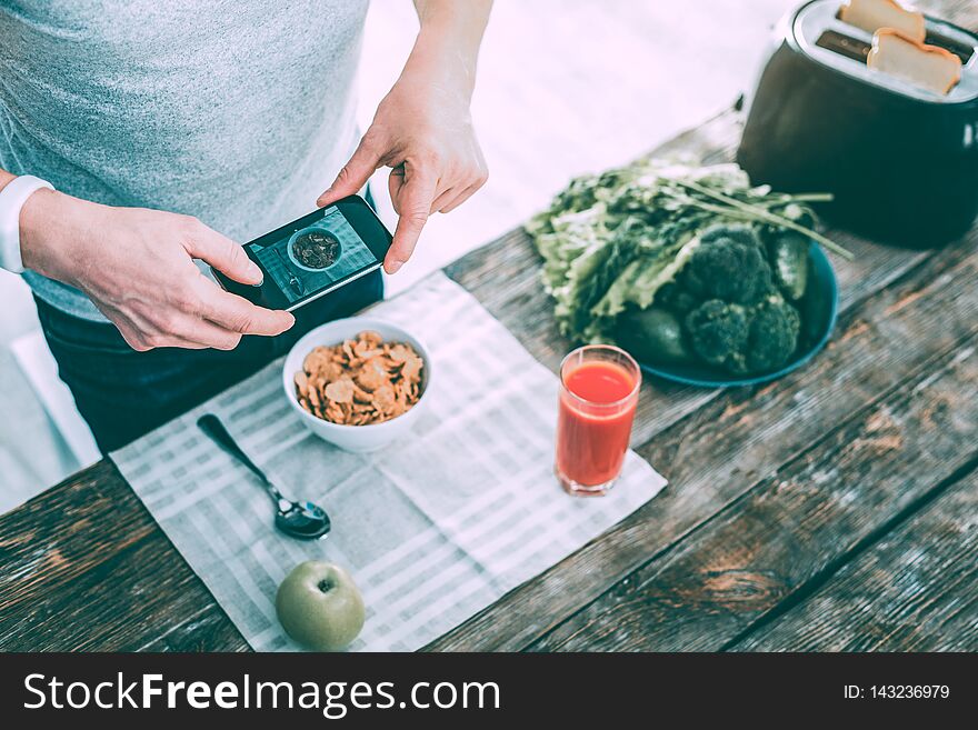 Modern involved man making a photo of his breakfast