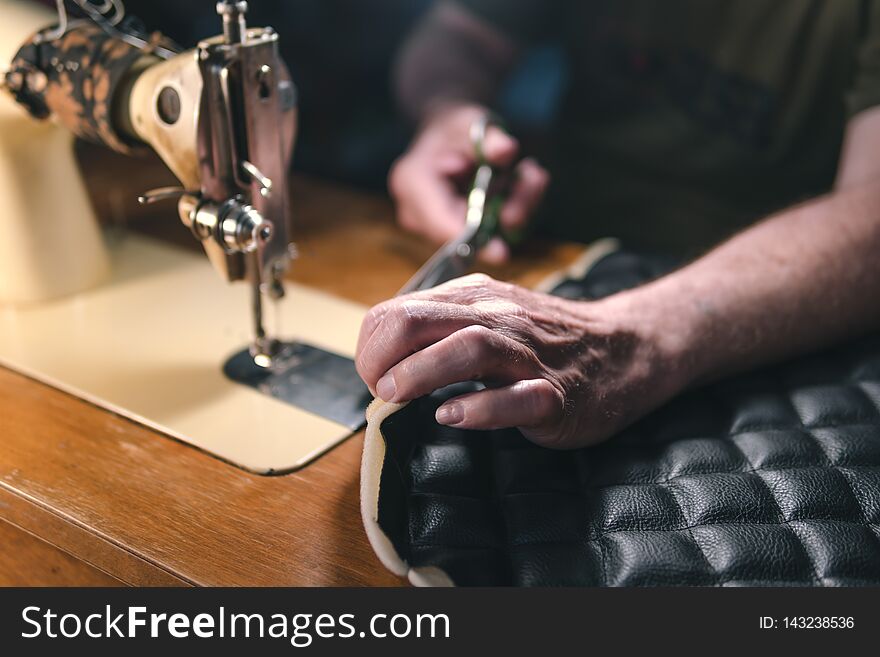 Sewing process of the leather belt. old Man`s hands behind sewing. Leather workshop. textile vintage sewing industrial