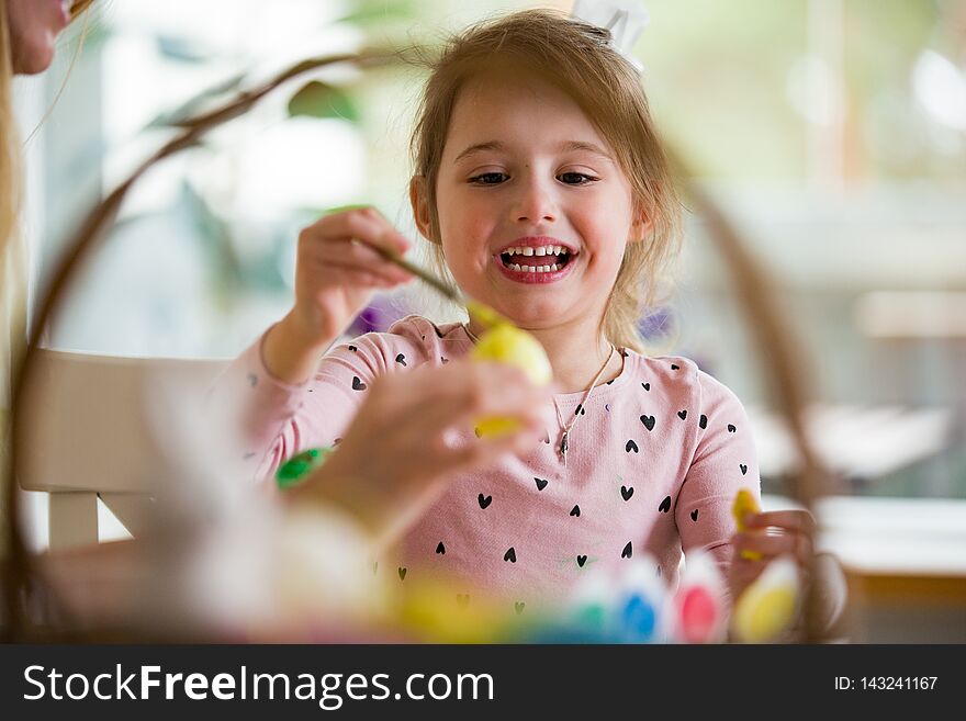 A mother and daughter celebrating Easter, painting eggs with brush