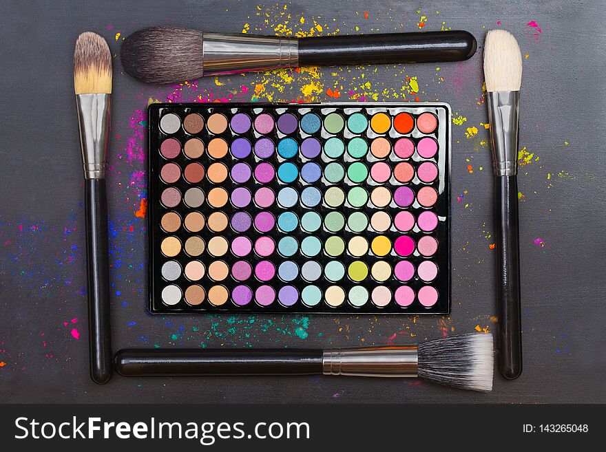 Flat lay of colorful eyeshadow palette with professional brushes on black background. Flat lay of colorful eyeshadow palette with professional brushes on black background