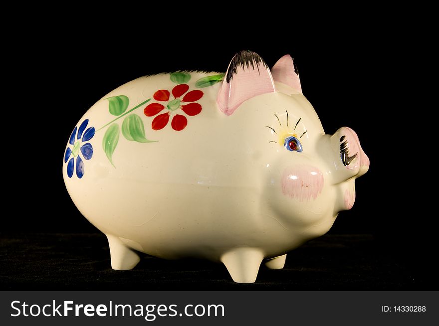 Old china piggy bank with flower pattern on a black background in portrait format