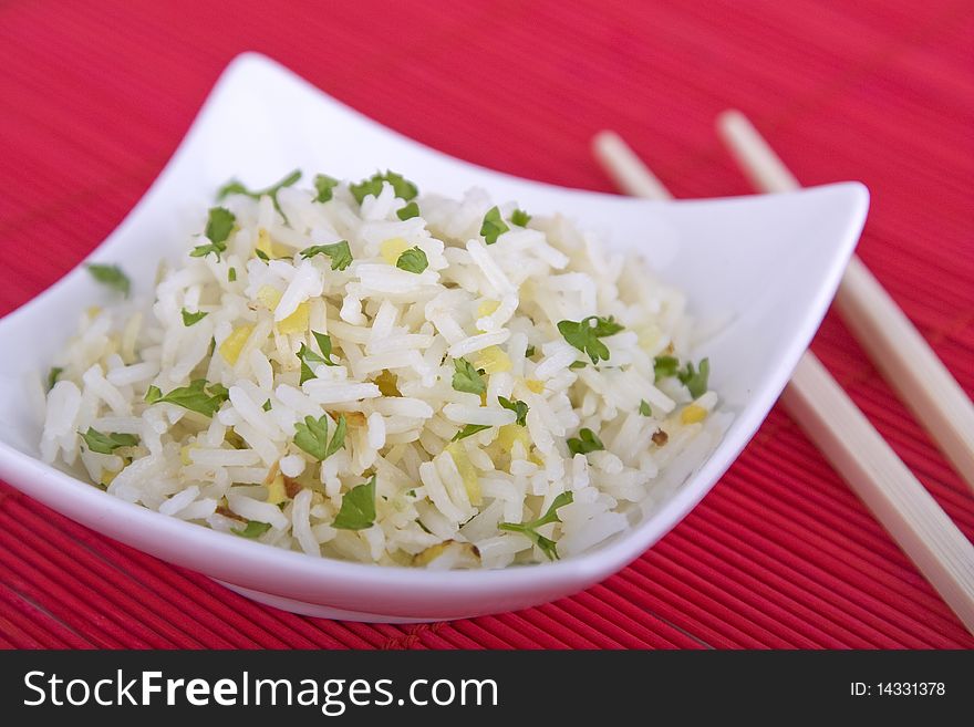 Bowl of rice with chopsticks on a red background