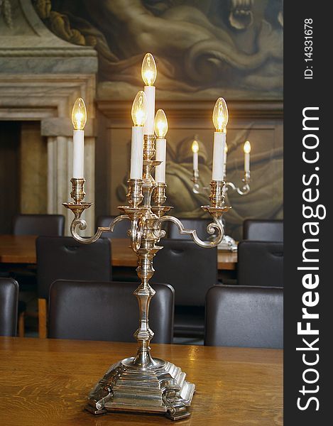 Candlestick with five candles-bulbs on wooden table in dining-room of old royal naval college, Greenwich, London, UK. Candlestick with five candles-bulbs on wooden table in dining-room of old royal naval college, Greenwich, London, UK.