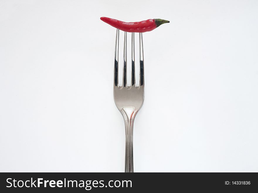 Red chili pepper on fork isolated on white background