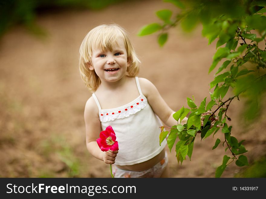 Happy small girl with tulip outdoors in sunny day. Happy small girl with tulip outdoors in sunny day