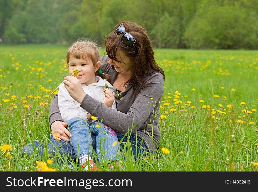 Mum with a daughter collect dandelions in medow
