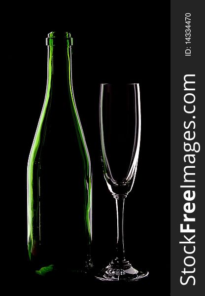 Green glass bottle of wine and wineglass on black background