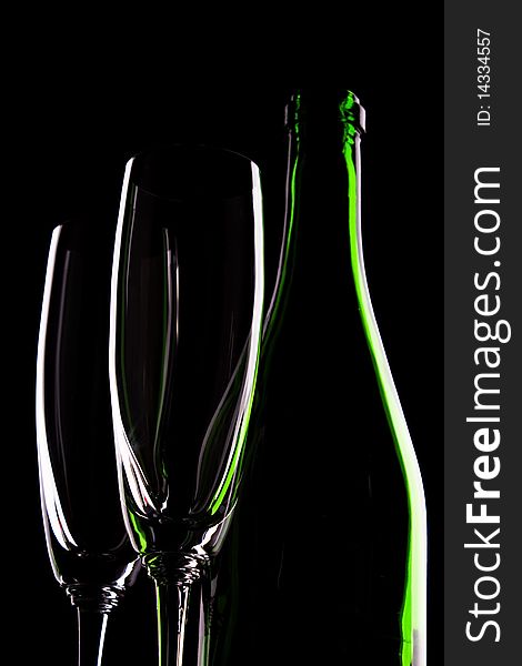 Green glass bottle of wine and wineglasses on black background