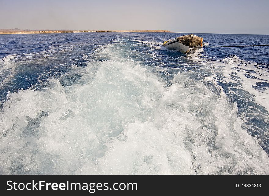 View of the wake of a motor yacht towing a small inflatable boat