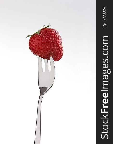 Single ripe fresh strawberry on fork isolated on white. Clipping path included