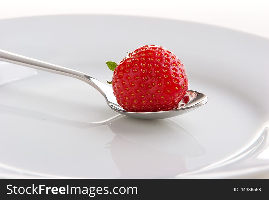 Single ripe fresh strawberry on spoon isolated on white.