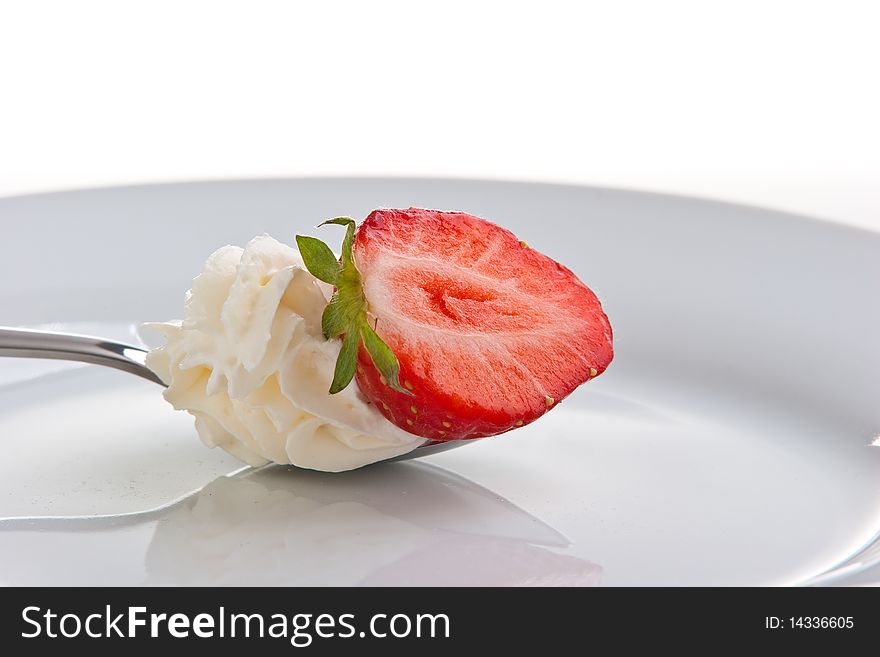 Single ripe fresh strawberry on spoon with cream isolated on white.