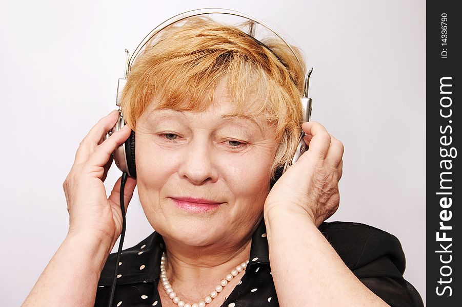 Old woman listens to music through earphones