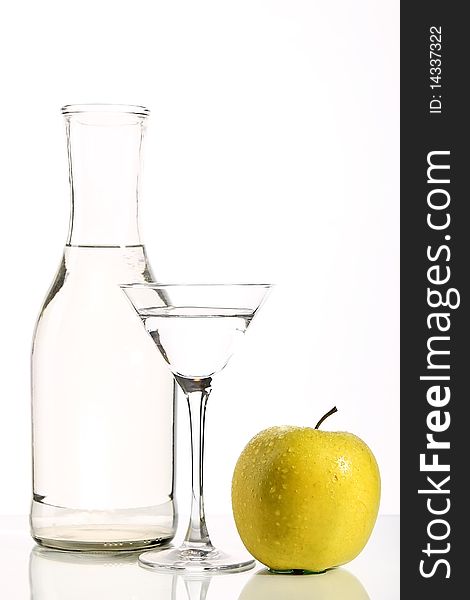 Bottle with transparent water, a glass and apples on a white background