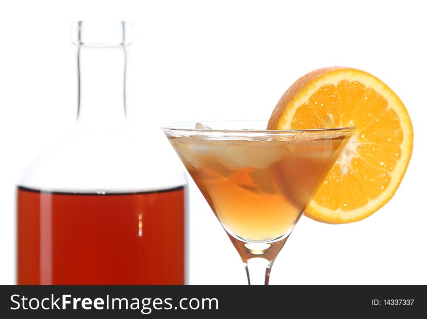 Bottle with an alcoholic drink, a glass and an orange on a white background