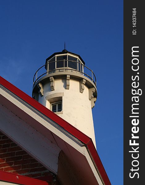 The Tawas Point Lighthouse in East Tawas, Michigan, set against a bright blue sky background.