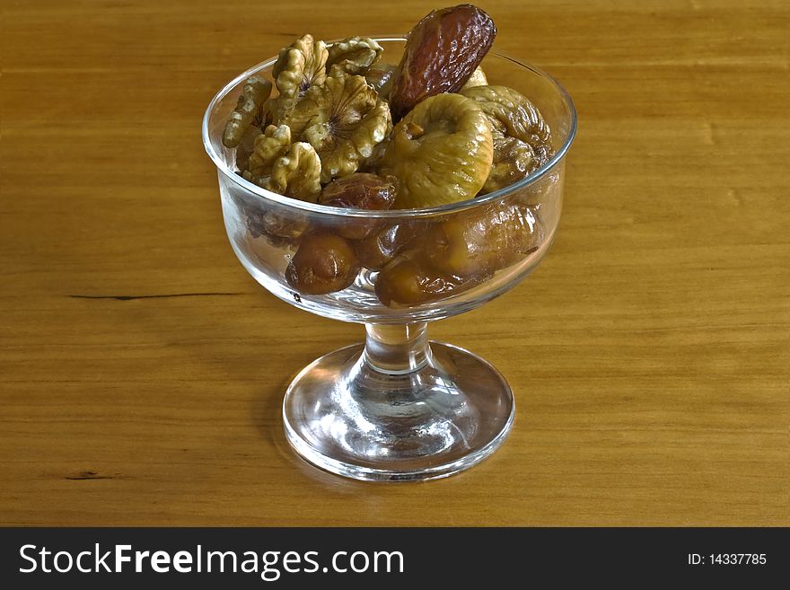 A glass dessert bowl containing figs, dates and walnuts. A glass dessert bowl containing figs, dates and walnuts