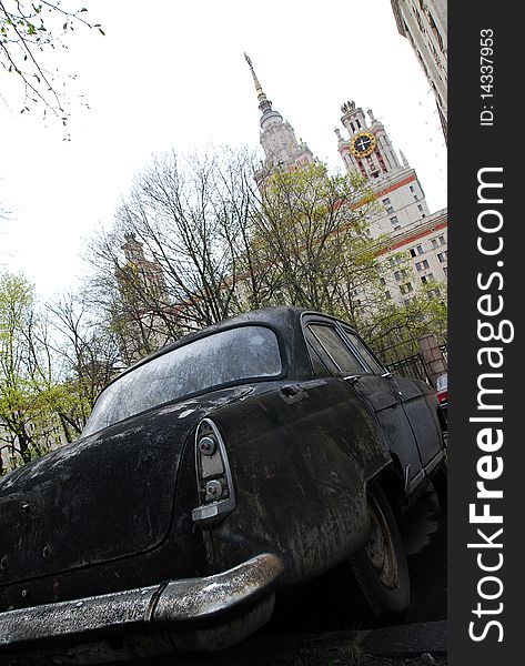 Old car on a background of trees and high-rise building